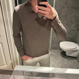 Brun pikétröja  - Säljer en stilren beige/brun pikétröja i mjuk ull med klassisk krage och tre knappar framtill. Den är i riktigt skönt material och riktigt bra skick. Jag är 188cm och bär storlek M. Hör av er vid frågor ;)