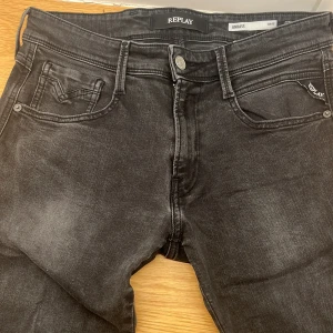 Replay Anbass svarta slim jeans 30 - Svarta Replay Anbass jeans i slim fit med klassisk femficksdesign och snygga detaljer på bakfickorna. Jeansen har en lätt tvättad look och är tillverkade i stretchigt denim för en bekväm passform. Perfekta för dig som gillar en smal siluett. Använda fåtal gånger.
