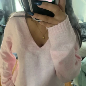 Ljusrosa stickad v-ringad tröja - Supermjuk och mysig ljusrosa stickad tröja med v-ringning och långa ärmar. Perfekt för att få en söt och chill look. Tröjan har ribbade muddar vid ärmsluten och är lätt oversized för extra komfort.