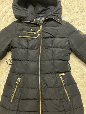 Hollies dunjacka – svart, strl 34 🖤 - 🧥 Stilren och varm vinterjacka från Hollies Stockholm ✨ Svart yttertyg med snygga gulddetaljer och dragkedjor 🐆 Trendigt leopardmönstrat innerfoder som ger det lilla extra  📏 Storlek: 34 👍 Bra skick, hel och fräsch ❄️ Perfekt för kalla dagar – både vardag och fest  Redo att användas direkt! 😊