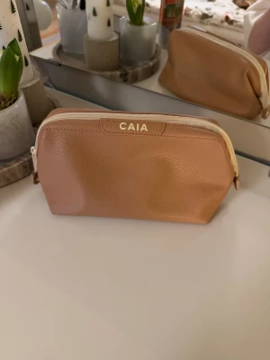 Beige sminkväska från CAIA - Säljer min Caia necessär eftersom jag köpt en ny. Den är i mycket bra skick och den har använts få tillfällen. Just denna finns inte att köpa längre. Man får plats med mycket, se sista bilden. Allt det får jag ner i necessären och då går den att stänga. Hör gärna av dig vid frågor❤️