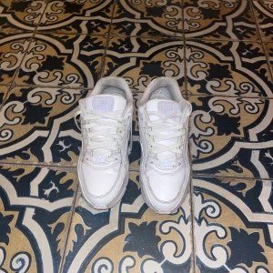 Nike Air Max  - Säljer ett par fräscha Nike Air Max sneakers i helvitt skinn med klassisk synlig Air Max-sula. Skorna har rund tå, snörning och diskreta detaljer i ljuslila på sulan. Perfekta för dig som gillar stilrena och sportiga sneakers med retrovibe. Köpta för 1500kr.