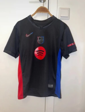 Fc Barcelona t-shirt  - En barça t-shirt. Svart, röd och blå med Lamine yamal på ryggen. Använd bara ca tre gånger då den är för liten. Stolek 140-148 11-12 år.