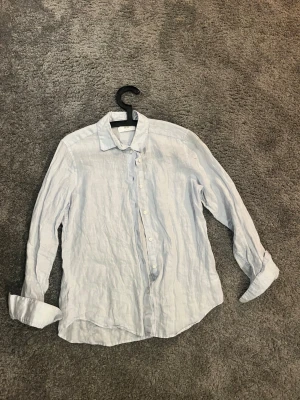 Ljusblå linneskjorta från Uniqlo XS - Fräsch ljusblå skjorta från Uniqlo i storlek XS, tillverkad i svalt linne. Skjortan har klassisk krage, långa ärmar och knappar framtill. Perfekt för dig som gillar en chill och stilren look med naturligt material. Passar dig som är ca 165-175. MVH 