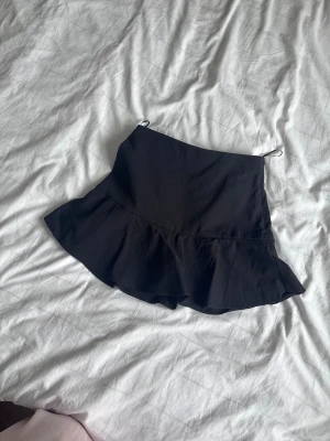 Svart skott från Zara - Supersnygg svart kort skort från Zara med volang nertill med hög midja! PRISET KAN DISKUTERAS! 