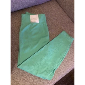 Mintgröna träningstights från Move - Mintgröna träningstights från Move med snyggt vågigt ribbat mönster. Hög midja och stretchigt material som sitter skönt och följer kroppen. Perfekta för gymmet eller yoga. Fräscha och trendiga färgen gör dem till ett riktigt statement. Aldrig använda.