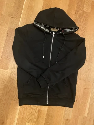 Burberry zip hoodie - Jag säljer min svarta burberry zip eftersom den har blivit lite för liten för mig nu. Den är i perfekt skick och använde den knappt. Om ni vill ha fler bilder är det bara att skriva så skickar jag. Finns i Stockholm om nån vill mötas annars fraktar jag också.