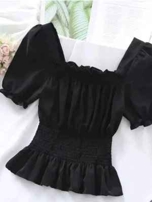 Svart offshoulder bandeau topp - Säljer en svart bandeau topp med offshoulder-design och volangdetaljer upptill och vid ärmarna. Toppen har en smockad midja som ger en tight och snygg passform. Perfekt för dig som vill ha en trendig och cool look.