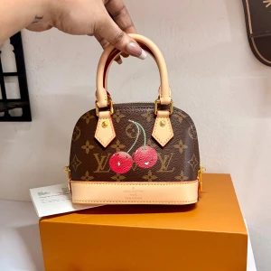 Limited Edition LV Alma - Ikonisk Louis Vuitton Alma BB Cherry — limited Murakami edition 🍒 Klassisk monogram canvas med lekfull körsbärsprint, en hyllning till 2000-talets mest ikoniska LV-era. Som ny, komplett med dustbag, axelrem, lås & köpkvitto från eBay (visas på bild).  Den här väskan är ett samlarobjekt och säljs sällan i detta skick. Allt som visas i annonsen skickas. Inkluderas låda 🎀 Priset är satt lågt för snabb affär – en once in a lifetime chans att få tag på denna pärla.