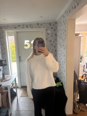 Vit stickad tröja från H&M - Mysig vit stickad tröja från H&M i storlek S. Tröjan har en högre rund hals, långärmad passform och är lite croppad. Materialet är fluffigt och mjukt, perfekt för kyligare dagar. Enkel och clean look som är lätt att styla.