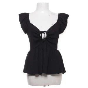 Svart blus med snörning och volang - Säljer en supersöt svart blus från Lager 157 med urringning och snörning fram till, toppen är inprincip aldrig använd så den har ett fint skick! Storlek xs, skriv för egna bilder🖤