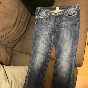 Blå Lee Scarlett jeans W31 L31 - Snygga blå Lee Scarlett jeans med klassisk femficksdesign och gul kontrastsöm. Jeansen har en något tvättad look och raka ben. Tillverkade i bomull och passar perfekt för dig som gillar en tidlös stil.