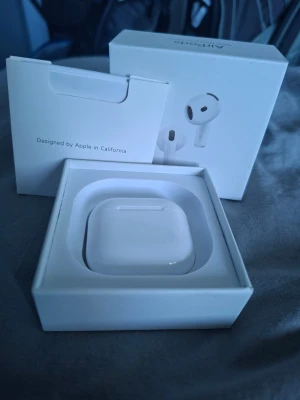 Apple AirPods 4 (ANC) - Apple AirPods 4 (ANC) med originalförpackning och laddningsetui. Trådlösa hörlurar med aktiv brusreducering. Dessa har garanti till 13 juli 2026 och ett valid serie nummer.