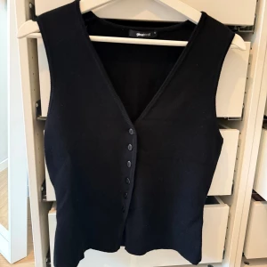 Svart stickad väst från Gina Tricot - Svart stickad väst med v-ringning och knappar framtill från Gina Tricot.  Aldrig använd, storlek S.