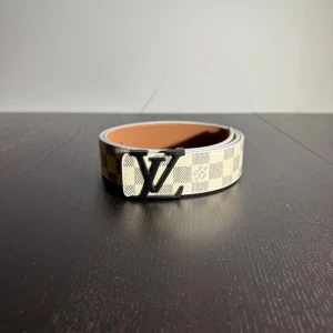 Bälte  - Helt nytt bälte i rutigt vit med svart unik logga