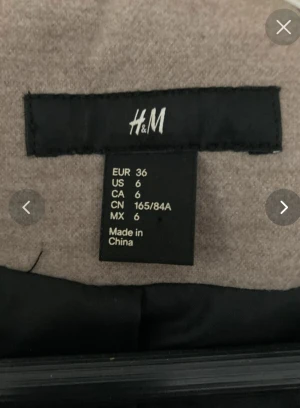 Beige skepparkavaj från H&M, strl 36  - Snygg beige skepparkavaj från H&M i storlek 36. Jackan har dubbelknäppning med svarta knappar, bred krage och dekorativ knappdetalj bak. Materialet är mjukt och känns som ullmix. Perfekt för dig som gillar klassisk stil med modern touch.