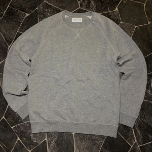 Pier One Sweatshirt  - En enkel och stilren grå sweatshirt från Pier One med rund hals och ribbade muddar. Tröjan har långärmad design och är tillverkad i mjuk bomull, perfekt för chill dagar. Snygg att matcha med jeans eller joggers.