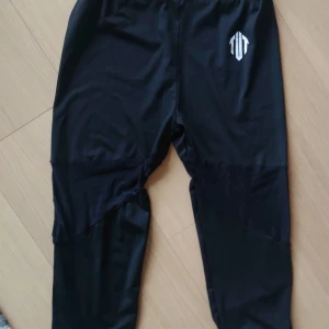 Svarta träningsbyxor med meshdetaljer, 3/4 längd, dam, M - Snygga svarta träningsbyxor från TUT med coola meshpaneler på benen för extra ventilation. Byxorna har en slim passform och är gjorda i mjukt syntetmaterial som känns skönt mot huden. Perfekta för gymmet eller löprundan.