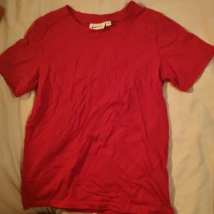 Röd t-shirt från Kappahl XS - En enkel röd t-shirt från Kappahl i storlek XS. Modellen har rund hals och korta ärmar, perfekt för dig som gillar basic och stilrent. Materialet är mjuk bomull som känns skönt mot huden. Passar dig som vill ha en klassisk och bekväm t-shirt.