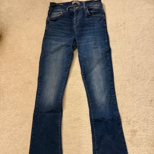 Blå jeans från LTB med utsvänga ben - Snygga blå jeans från LTB med klassisk femficksdesign och kontrastsömmar. Modellen har utsvängda ben och normal passform, med coola detaljer på bakfickorna. Perfekt för dig som gillar en enkel och stilren look.