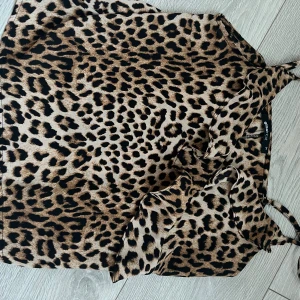 Leopardmönstrad blus från Gina Tricot - Säljer ett snyggt linne från Gina Tricot i leopardmönster. Blusen har volangdetaljer framtill och är gjord i ett lätt, mjukt material. Färgerna är beige och svart med bruna inslag. XS-M.