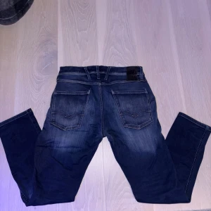 Replay Anbass jeans  - Snygga Replay Anbass jeans i mörkblå tvätt med coola slitningar och klassiska fem fickor. Modellen har raka ben och normal passform, med detaljerade sömmar på bakfickorna och logopatch i midjan. Perfekt för dig som gillar stilrena jeans med lite edge. Pris kan diskuteras. Vid frågor är det bara att höra av sig. 