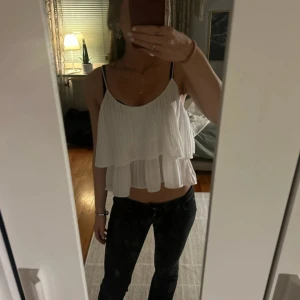 Vit volangtopp - Supersöt vit linnetopp från BikBok med dubbla volanger och tunna axelband. Toppen är plisserad och har en luftig, flowy känsla som är perfekt för varma dagar. Sitter croppad och har en lätt och somrig vibe. använd fåtal gånger! 💕