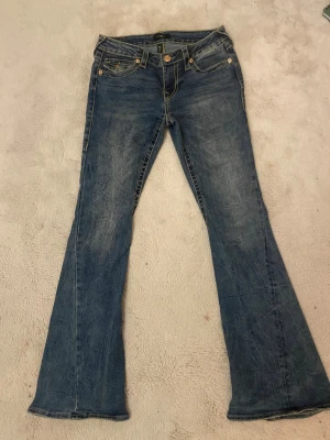 True Religion Joey Low Rise Flare jeans - Säljer ett par blå True Religion Joey Low Rise Flare jeans med snygga flaps! Ny pris: 1800kr på jeans Uno!