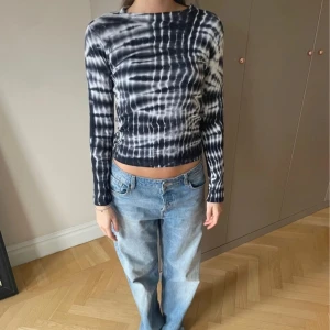 Blåvit långärmad tie-dye tröja - Snygg långärmad tröja med blåvit tie-dye mönster. Modellen är slim och har en rund halsringning. Materialet känns mjukt och stretchigt, perfekt för dig som gillar en cool och trendig look. Passar dig som vill sticka ut med ett unikt mönster.