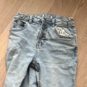 Ljusblå jeans med knappgylf -  Byxor som tyvärr har blivit för små i storlek -140 ungefär de har krympt pyttelite i tvätten så att jag kan inte ha dem längre