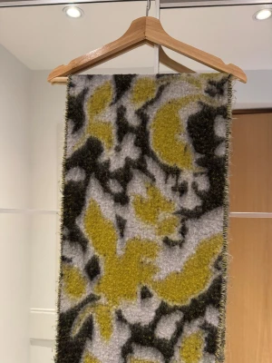 Soft chunky fringed scarf - Snygg och mjuk halsduk med blommigt mönster i gult, vitt och svart. Den är rektangulär med fransar i ändarna och har en fluffig, stickad känsla som gör den perfekt för kyliga dagar. Perfekt accessoar för att lyfta din outfit. Härlig och snygg mönstrad mjuk stor halsduk med fransar och borstad finish. Storlek: 200x35cm.