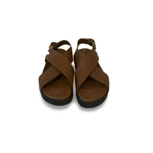 Bruna sandaler med korsade remmar - Snygga bruna sandaler från & other stories med breda korsade remmar och justerbart spänne vid ankeln. Sandalerna har en platt sula med korkdetalj och svart undersida. Tillverkade i skinn för en stilren och klassisk look, perfekta för varma dagar.