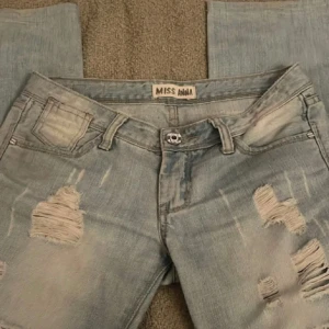 Ljusa ripped jeans från Miss Anna - Säljer ett par ljusblå jeans från Miss Anna med slitna detaljer och snygga ripped-effekter på benen. Modellen har klassisk femficksdesign, normal passform och raka ben. Perfekt för dig som gillar en avslappnad och trendig stil.