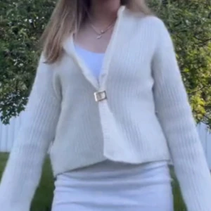 Vit ribbad kofta - Säljer en vit ribbad kofta med lång ärm. Koftan har en mjuk och stickad känsla, perfekt att slänga över en topp. Den har en lite loose passform och är enkel att matcha med olika outfits.