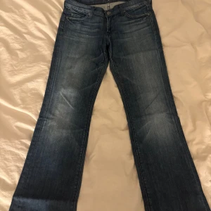 Bootcut jeans från 7 For All Mankind - Snygga lågmidjade bootcut jeans från 7 For All Mankind, med detaljer på bakfickorna. Är avklippta längst ner, passar mig som är 164cm. Storlek 30, passar mig som har 36 men skulle tro att de passar 38 också.