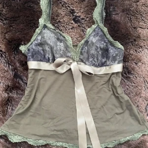 Topp med spets och rosa rosett - Säljer en olivgrön linnetopp med spets och rosett  i storlek S💕
