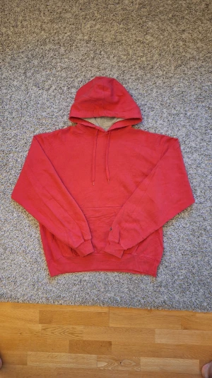 Röd Champion hoodie  - Riktigt chill röd hoodie från Champion i storlek L. Använd fåtal gånger och skicket är riktigt bra, inga slitningar eller defekter finns. Den har dock lite creasningar, som går bort enkelt med lite strykning. Passar superbra för dig som gillar en mer chill stil. Skick: 8/10