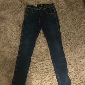 Replay Anbass Hyperflex jeans blå 29/32 - Snygga Replay Anbass Hyperflex jeans i mörkblå färg med slim fit och klassisk femficksdesign. Jeansen har kontrastsömmar, raka ben och är tillverkade i stretchigt jeansmaterial för extra komfort. Passar dig som gillar stilrena och moderna jeans.