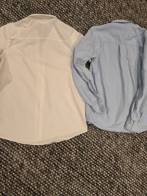 Vit och ljusblå skjorta - Två stilrena skjortor säljes 😁 Båda är i mjuk bomull och har riktigt schysst passform 🙌 Vid minsta funderingar hör av er👍