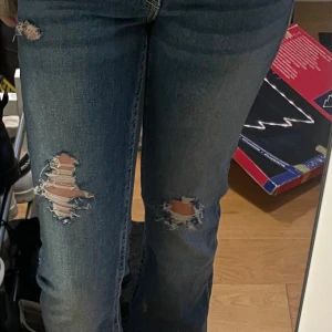 Blå jeans med slitningar   - Säljer ett par blå jeans med snygga slitningar på benen och med snygga fickor . 