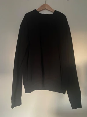 Svart HM basics sweatshirt XS - En enkel svart sweatshirt i klassisk modell från HM BASICS. Tröjan har rund hals, ribbade muddar vid ärmslut och nederkant samt långärmad passform. Perfekt för chill dagar och passar till allt. Materialet är mjuk bomull som känns skönt mot huden.