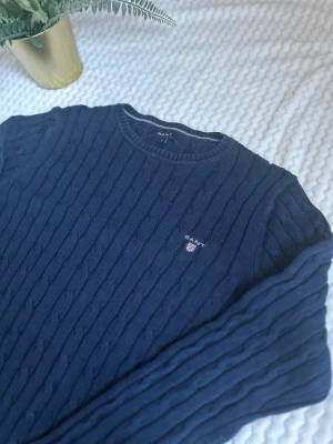 Marinblå kabelstickad tröja GANT - Säljer en snygg marinblå kabelsrickad tröja från Gant med rund hals och broderad logga på bröstet. Har ni frågor så är det bara att säga till. Priset kan alltid diskuteras❗️Ordnarie pris 1599kr.