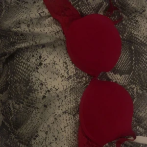 Röd bh med spetsdetaljer - Snygg röd bh med vadderade kupor och spetsdetaljer på sidorna. Perfekt för att ge en trendig och feminin look. Axelbandslös design som passar till många olika outfits.