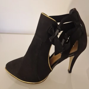 Unika klackar - Dessa skor har en unik design med utskärningar och dekorativa band. Perfekt för en stilfull look. De är inköpta i New York. Endast provade och säljes då de ej har kommit till användning. Snygga till höstens event. 