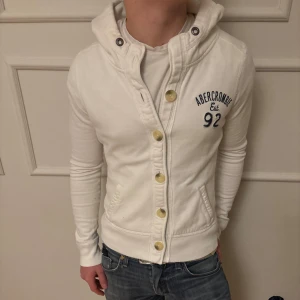 Abercromie & fitch hoodie/cardigan - Säljer nu en otroligt fet abercromie&fitch hoodie/cardigan! Det saknas en knapp högst upp men den lär inte andvändas och det syns knappt. Vid köp så kan man få önska att knapp ”hålet” sys igen!                                                                                   Pris kan diskuteras!