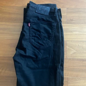 Svarta Levi's 514 jeans W31 L30 - Svarta Levi's 514 jeans med klassisk femficksdesign och diskret röd logga på bakfickan. Jeansen har rak passform och är tillverkade i slitstarkt bomullstyg. Perfekta för dig som gillar en clean och tidlös look.
