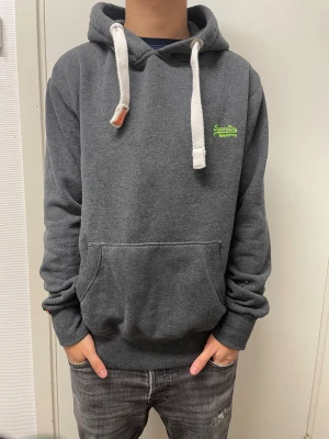 Superdry hoodie - Fet mörkgrå hoodie från Superdry. Väldigt bra skick. Modellen är 173cm, 64kg. Pris kan självklart diskuteras!!
