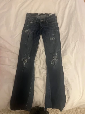 Mörkblå bootcut jeans från Hollister - Snygga mörkblå jeans från Hollister med bootcut passform och slitna detaljer framtill. Jag har själv sytt om jeansen till bootcut och gjort hålen säljer pga att de inte passar i midjan längre, passar bra i längden på mig och jag är 163 🙂