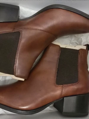Bruna chelsea boots Vagabond strl 36 - Snygga bruna chelsea boots från Vagabond i modellen Marja. Skorna är tillverkade i skinn med elastiska svarta paneler på sidorna och har en låg klack samt spetsig tå. Perfekt för dig som gillar stilrena och klassiska boots med modern touch.