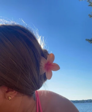 Hibiskus hårklämma i ljusrosa - Säljer en superfin hårklämma formad som en blomma i ljusrosa och röd ton. Klämman har fem kronblad och är gjord i blank plast, perfekt för att sätta upp håret på ett gulligt sätt. Passar dig som vill ha en söt och somrig vibe i håret.